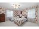 Comfortable bedroom with twin beds, floral wallpaper, and abundant natural light from two windows at 301 Waterwood Dr, Yalaha, FL 34797