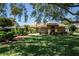 Beautiful brick home featuring a lush lawn, manicured landscaping, and a clay tile roof at 301 Waterwood Dr, Yalaha, FL 34797