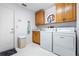 Bright laundry room features cabinetry, sink, washer, and dryer with white walls and tile floors at 301 Waterwood Dr, Yalaha, FL 34797