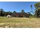 Wide view of the home and backyard featuring a screened lanai and a storage shed in the distance at 30554 Quince Ave, Eustis, FL 32736