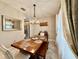 Bright dining area featuring a modern chandelier, a rustic dining table, and elegant curtains at 30554 Quince Ave, Eustis, FL 32736