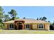Charming single-story home with tan stucco, red shutters, an arched entryway, and a well-manicured lawn at 30554 Quince Ave, Eustis, FL 32736