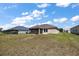 Rear exterior view of the home showcases the screened lanai and spacious yard at 3305 Dzuro Dr, Oxford, FL 34484