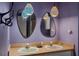 Modern bathroom with dual sinks, decorative lighting, vanity mirrors and vibrant purple walls at 333 Stanley Bell Dr, Mount Dora, FL 32757