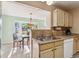 Open kitchen area with sink, tile backsplash, and view of outdoor scenery through dining room windows at 333 Stanley Bell Dr, Mount Dora, FL 32757