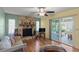 Living room with stone fireplace, wood floors, ceiling fan, and sliding glass doors at 33801 Picciola Dr, Fruitland Park, FL 34731