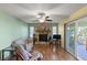 Living room with stone fireplace, wood floors, ceiling fan, and access to sun room at 33801 Picciola Dr, Fruitland Park, FL 34731