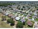 Expansive aerial view of a quiet neighborhood with tree-lined streets and well-maintained lawns adjacent to a golf course at 3614 Auburndale Ave, The Villages, FL 32162