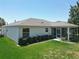 Back exterior of house with screened in patio and tidy, green yard at 3614 Auburndale Ave, The Villages, FL 32162
