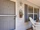 Cozy front porch with a gray door and an Easter basket accent at 3614 Auburndale Ave, The Villages, FL 32162