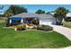 Charming home with manicured lawn, palm trees, blue awning and brick driveway in a well-kept community at 3614 Auburndale Ave, The Villages, FL 32162
