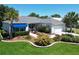 Beautifully landscaped home featuring lush green lawn, a blue awning, palm trees and a brick paved driveway at 3614 Auburndale Ave, The Villages, FL 32162