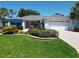 Beautiful home with well-kept lawn, palm trees, blue awning and brick driveway in a pristine community at 3614 Auburndale Ave, The Villages, FL 32162