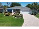Inviting single-story home boasts a manicured lawn, brick driveway, and lush landscaping at 3614 Auburndale Ave, The Villages, FL 32162