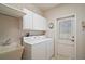 Functional laundry room with a utility sink, washer, dryer, storage cabinets, and exterior door for convenience at 3630 Oak St, Mount Dora, FL 32757