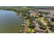 An aerial view of waterfront homes and private docks along a lake with lush greenery and partial views of a distant town at 38420 Langlois Pl, Leesburg, FL 34788