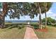 A brick path leads through the expansive backyard towards a private dock on the tranquil lake at 38420 Langlois Pl, Leesburg, FL 34788