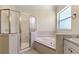 Bathroom with a glass enclosed shower, garden tub and a window letting in natural light at 38420 Langlois Pl, Leesburg, FL 34788