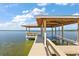 Lakeside dock featuring a covered seating area and a boat lift, perfect for enjoying waterfront activities at 38420 Langlois Pl, Leesburg, FL 34788