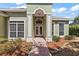 Inviting entryway featuring double doors, decorative columns, and a brick-paved walkway surrounded by landscaped gardens at 38420 Langlois Pl, Leesburg, FL 34788