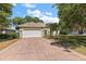 Charming single-story home with a two-car garage and brick-paved driveway, complemented by lush landscaping at 38420 Langlois Pl, Leesburg, FL 34788