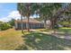 A home with a brick walkway and a large screened sunroom surrounded by palm trees and mature oak trees draped with Spanish moss at 38420 Langlois Pl, Leesburg, FL 34788
