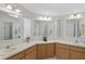 A bright bathroom featuring double sinks, large mirrors, and wooden cabinets at 432 King Way, Tavares, FL 32778