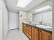 Spacious bathroom with dual sinks, wood cabinets, a skylight and tile flooring creating a luxurious experience at 500 Newell Hill Rd # 111A, Leesburg, FL 34748