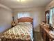 A cozy bedroom featuring floral bedding and a wood dresser with an abundance of light at 5029 Eagles Nest Rd, Fruitland Park, FL 34731
