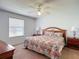 Bright bedroom featuring a ceiling fan, window and a colorful floral comforter set on the bed at 508 Carrera Dr, The Villages, FL 32159