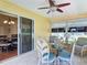Enclosed patio with a ceiling fan, a glass table and four wicker chairs at 508 Carrera Dr, The Villages, FL 32159