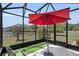 Screened-in patio with artificial turf, umbrella, and serene views of the surrounding landscape at 5220 Horsford Path, The Villages, FL 32163