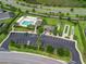Aerial view of community pool, shuffleboard courts, clubhouse, parking, and landscaping at 575 Wheelock St, The Villages, FL 32163