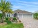 Charming single-story home features a well-manicured lawn, vibrant landscaping, and a paver driveway at 575 Wheelock St, The Villages, FL 32163