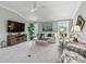Bright living room featuring neutral tones, a ceiling fan, and a view of the landscaped exterior at 575 Wheelock St, The Villages, FL 32163