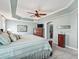 Comfortable main bedroom with tray ceilings, ceiling fan, and ensuite bathroom and walk-in closet at 575 Wheelock St, The Villages, FL 32163