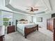 Serene main bedroom with a tray ceiling, plantation shutters, and classic wooden furniture at 575 Wheelock St, The Villages, FL 32163