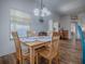 Well-lit dining area with a classic chandelier, wood table and chairs, offering a view into the cozy living spaces at 633 Jameston Ave, The Villages, FL 32162