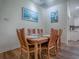 Cozy dining room features a wood table, six chairs, and beach-themed artwork with a view of the kitchen at 633 Jameston Ave, The Villages, FL 32162