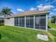Exterior view of a screened in sunroom surrounded by lush green grass at 633 Jameston Ave, The Villages, FL 32162