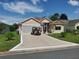 Charming single-story home with a well-manicured lawn and long driveway with decorative golf cart parked on it at 633 Jameston Ave, The Villages, FL 32162