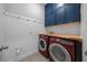 Laundry room with red washer and dryer, butcher block folding table, and blue cabinets at 677 Brooks Field Dr, Winter Garden, FL 34787