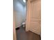 A compact toilet room with gray tile, a toilet, and a white door at 6846 Wilson Hammock Ave, Groveland, FL 34736