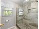 Modern shower with large gray tiles, glass door, and shower niche at 728 Tangerine Dr, The Villages, FL 32159