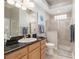 Bright bathroom features a black granite countertop, a glass-enclosed shower, and neutral tile flooring at 8715 Se 176Th Lowndes Pl, The Villages, FL 32162