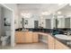 Bathroom featuring double vanities with granite countertops, mirrors, and a neutral color scheme at 8715 Se 176Th Lowndes Pl, The Villages, FL 32162