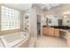 Bright bathroom featuring soaking tub, vanity with makeup area, and natural light from glass block window at 8715 Se 176Th Lowndes Pl, The Villages, FL 32162