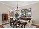 Formal dining room with chandelier, wood floors, and view to the kitchen and front yard through large windows at 8715 Se 176Th Lowndes Pl, The Villages, FL 32162