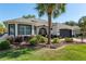 Beautifully landscaped home with palm tree features well-manicured lawn and two car garage creating curb appeal at 8715 Se 176Th Lowndes Pl, The Villages, FL 32162