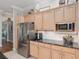 Bright kitchen features stainless steel refrigerator, black granite countertops and wood cabinets at 8715 Se 176Th Lowndes Pl, The Villages, FL 32162